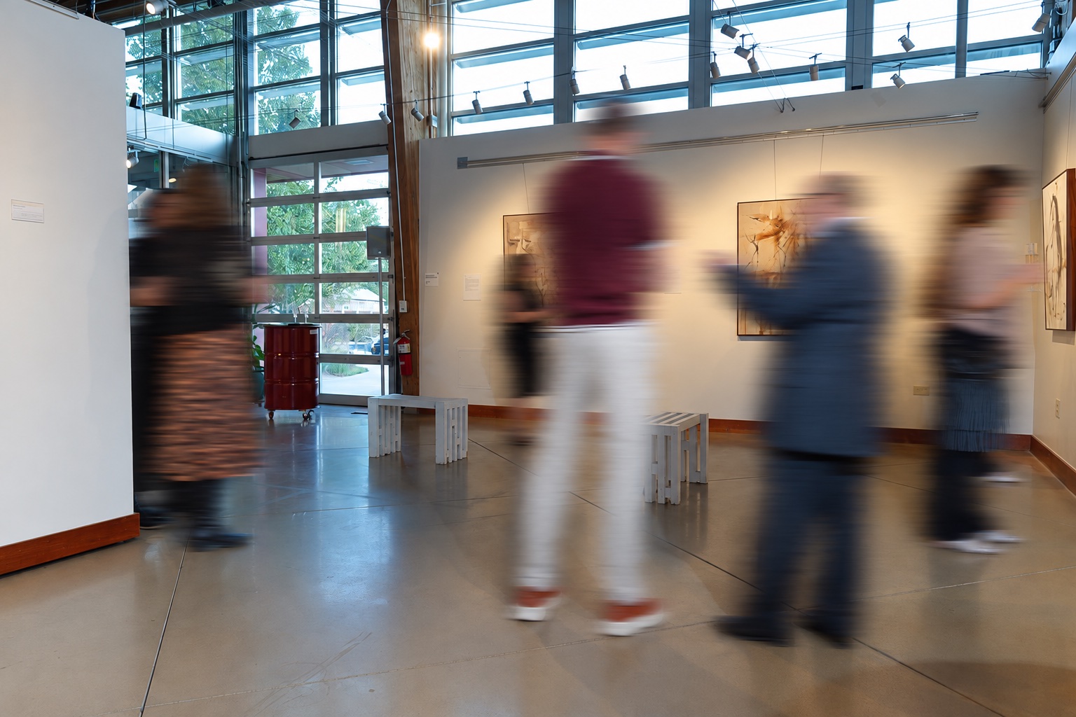 Opening-night conversations at Art Gym Denver, with motion-blurred visitors.
